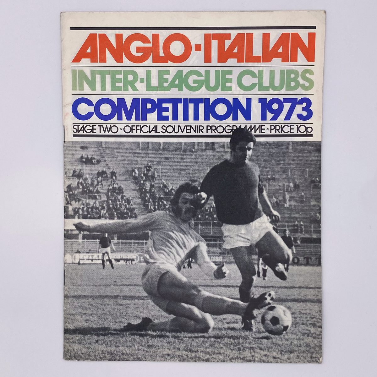 Cover of the 1973 Anglo-Italian Inter-League Clubs Competition programme featuring a black and white photo of two football players in action on the pitch, with the ball and goal visible in the background. The text on the programme reads 'ANGLO-ITALIAN INTER-LEAGUE CLUBS COMPETITION 1973 - SAGE TWO OFFICIAL SOUVENIR PROGRAMME - PRICE 10p'.